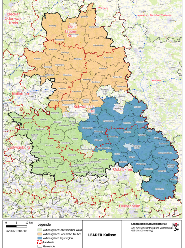 Eine detaillierte Karte von Landkreisen in Süddeutschland, die verschiedene LEADER-Aktionsgebiete farblich kodiert darstellt. Die Karte zeigt: Grünes Gebiet: Aktionsgebiet Schwäbischer Wald. Es umfasst Teile des Landkreises Ludwigsburg und reicht bis in den nordöstlichen Bereich hinein. Oranges Gebiet: Aktionsgebiet Hohenlohe-Tauber. Dieses Gebiet erstreckt sich über den gesamten Main-Tauber-Kreis und einen großen Teil des Landkreises Schwäbisch Hall. Blaues Gebiet: Aktionsgebiet Jagstregion. Es beinhaltet große Teile des Ostalbkreises und einen Teil des Landkreises Schwäbisch Hall. Die Karte zeigt auch umliegende Städte und Landkreise, darunter Heilbronn, Neckar-Odenwald-Kreis, Würzburg, Ansbach, Heidenheim, und weitere. Grenzen der Landkreise sind mit schwarzen Linien markiert, während Gemeindegrenzen in roten Linien dargestellt sind. Eine Legende am unteren Rand der Karte erklärt die Farbgebung der Aktionsgebiete und die Bedeutung der verschiedenen Linien. Der Maßstab der Karte beträgt 1:300.000. Die Karte wurde vom Landratsamt Schwäbisch Hall, Amt für Flurneuordnung und Vermessung, erstellt.