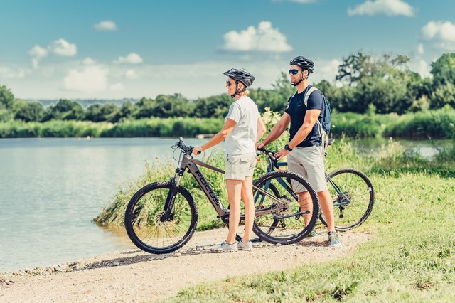 Ein Mann und eine Frau stehen mit ihren Fahrrädern am Ufer und blicken über den Starkholzbacher See